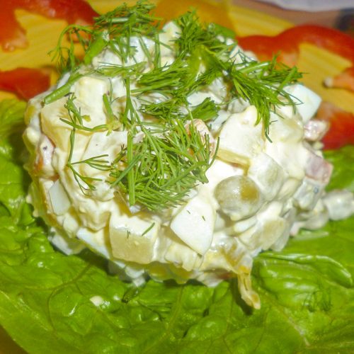 Un dome de salade Olivier enfoui dans la mayonnaise et parsemé d'aneth